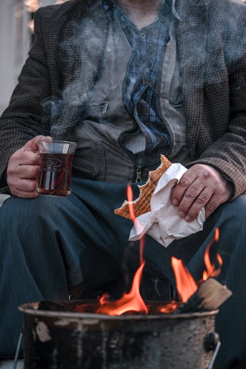 A man is sitting on a bench with a cup of tea