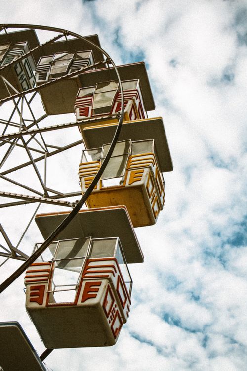 Free Low-angle view of a vibrant ferris wheel against a cloudy sky, capturing urban amusement Stock Photo