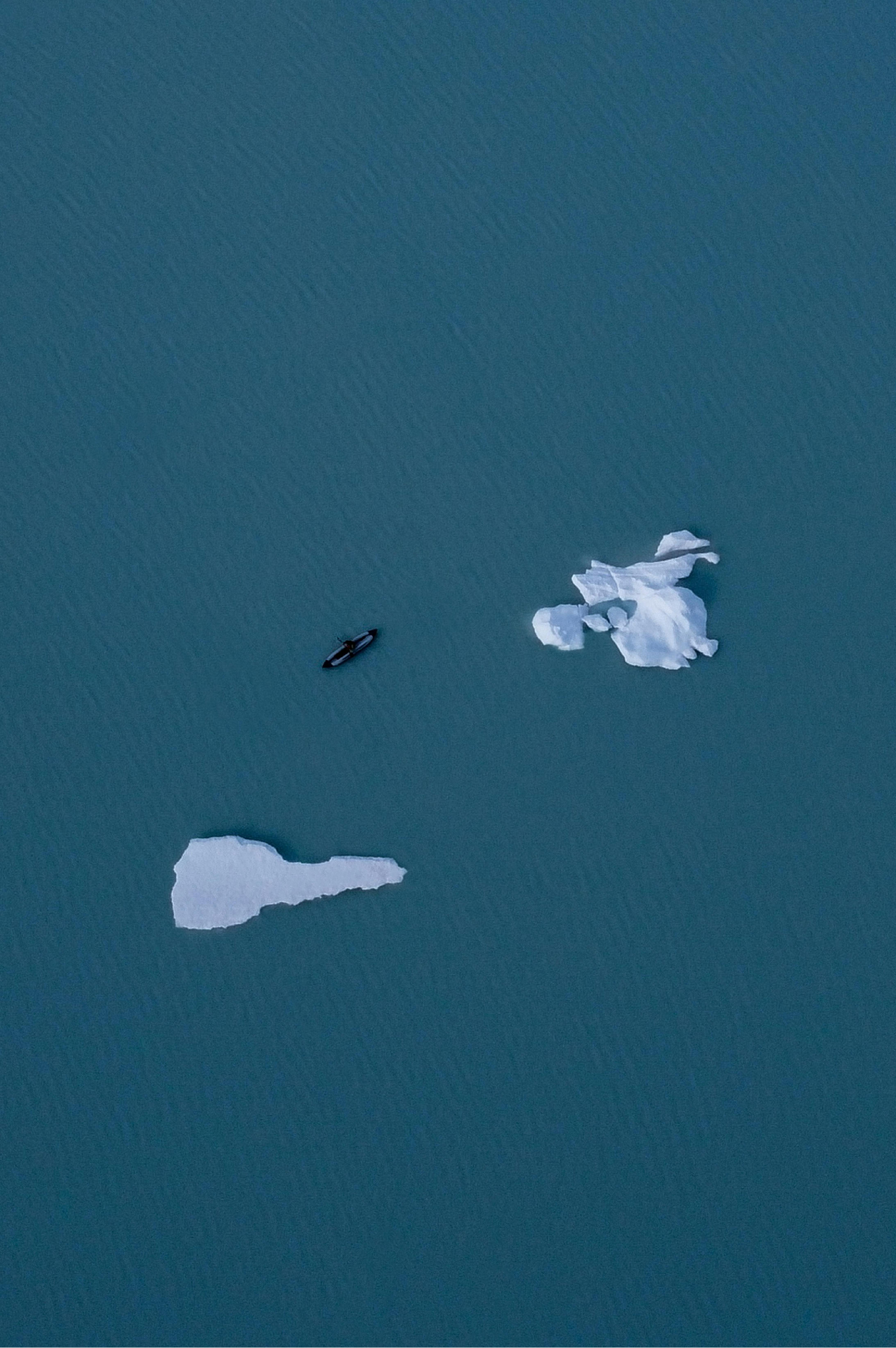A minimalist aerial shot of icebergs and a vessel in the cold waters of Ushuaia, Argentina.