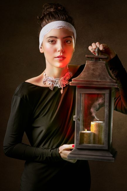 Elegant woman posing with a vintage lantern, exuding a classic and moody atmosphere.