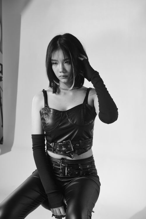 Free Monochrome portrait of a woman in a leather outfit, sitting in a studio. Stock Photo