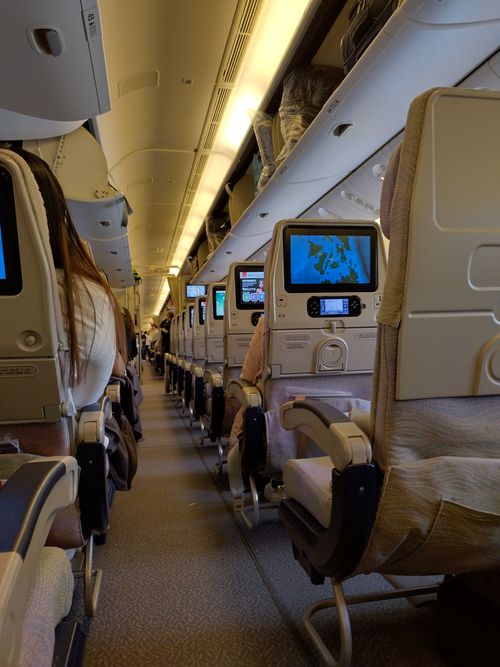 Free View of an airplane cabin interior with passengers seated, featuring screens on seatbacks. Stock Photo