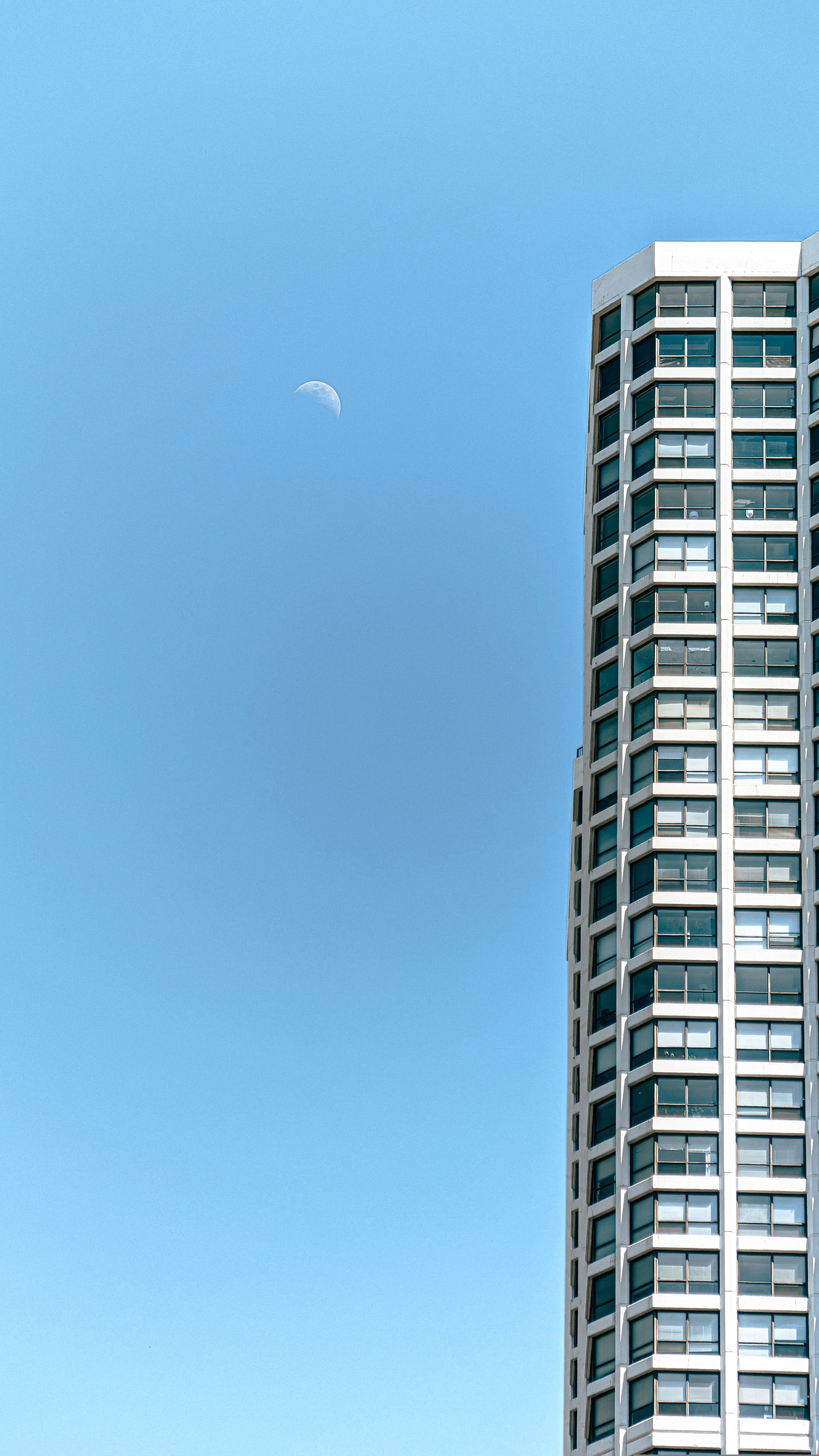 A tall building with a moon in the sky · Free Stock Photo