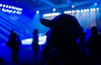 夜生活活动中，灯光明亮，映出一个戴帽子的人的剪影