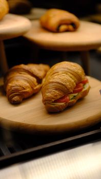 Tasty croissants with fresh vegetable fillings displayed on wooden trays.