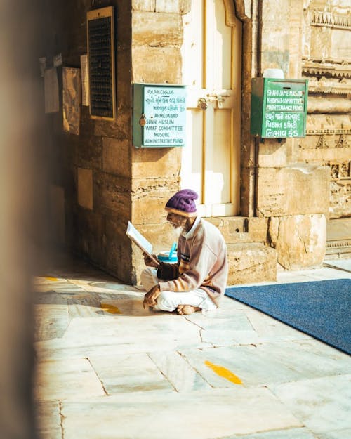 A man sitting on the ground reading a book