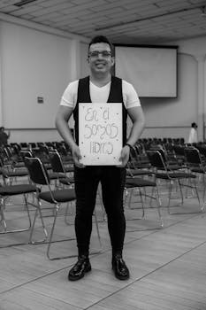 A smiling man holds an inspirational sign in a hall in Mexico City.