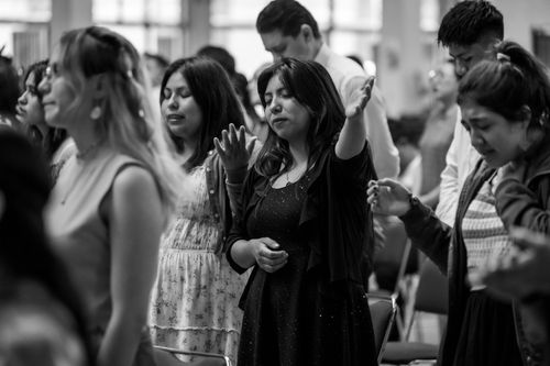 Free A diverse group of people with raised arms praying at an indoor religious gathering in Ciudad de México. Stock Photo