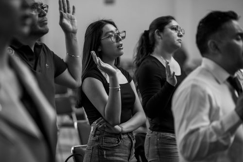 Free Black and white image of a worship gathering in Mexico City with people praying and raising hands. Stock Photo