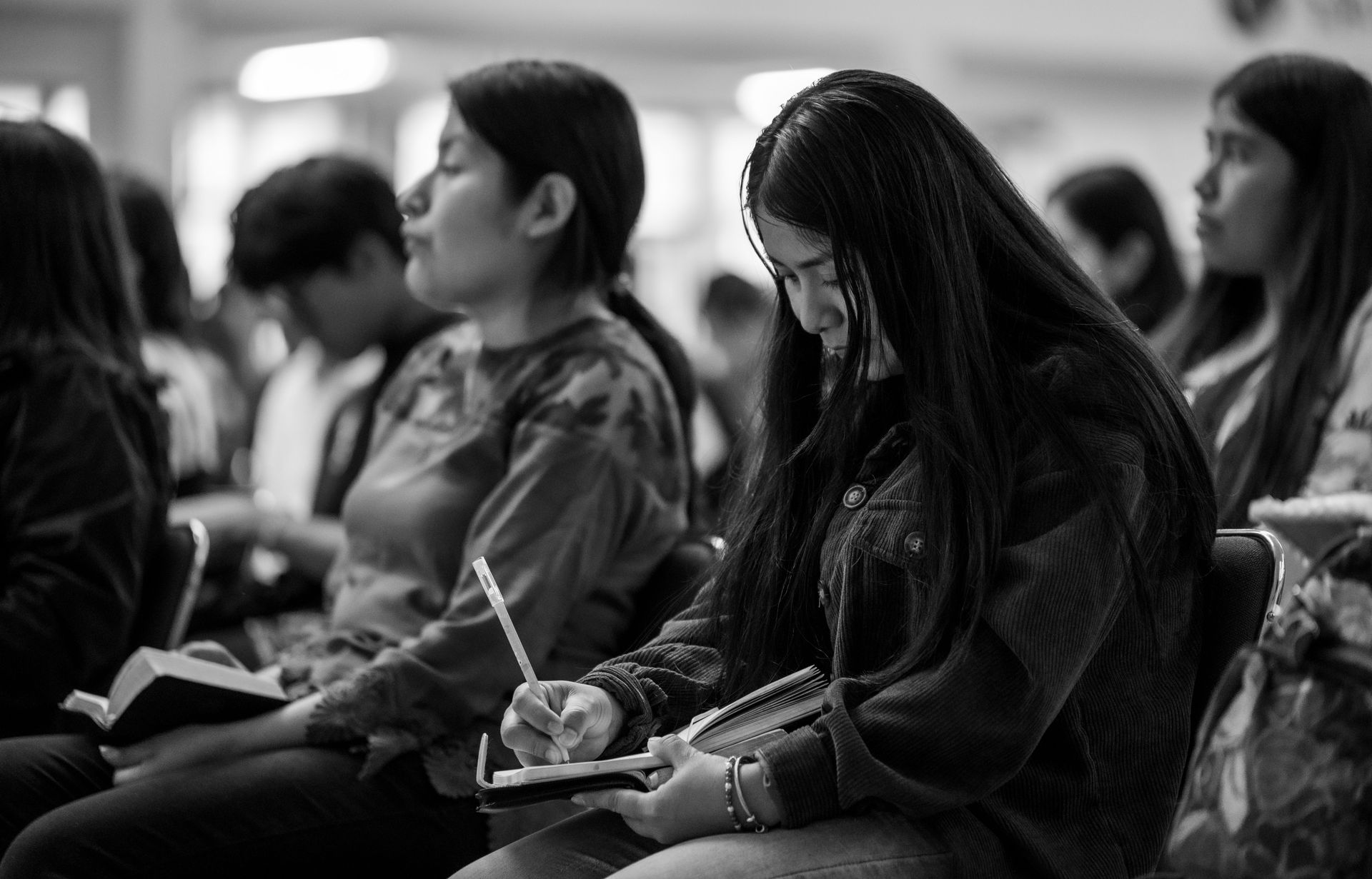 A focused young woman writing in a notebook during a group gathering in Ciudad de México.