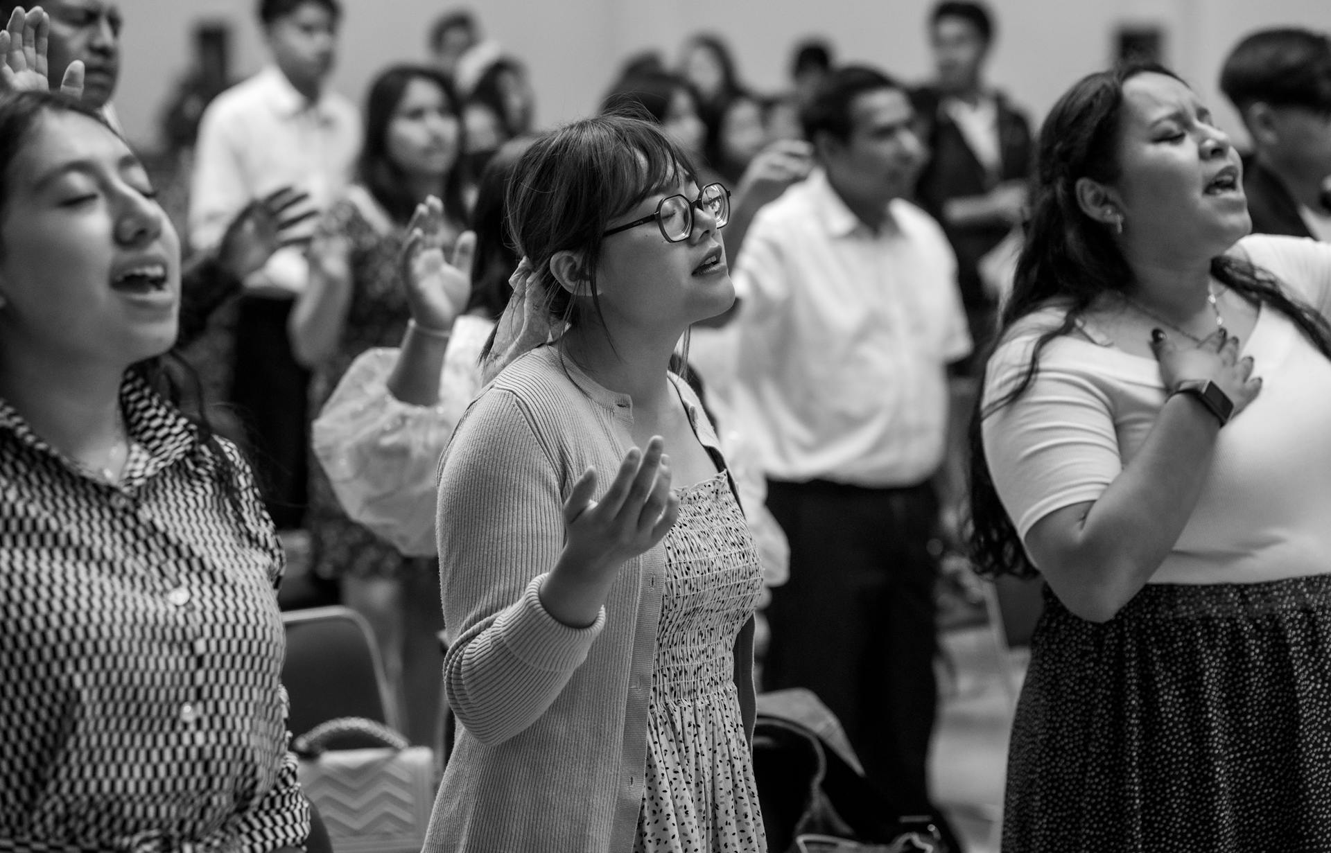 Black and white photo of diverse group praying and worshiping at a church event in Ciudad de México.