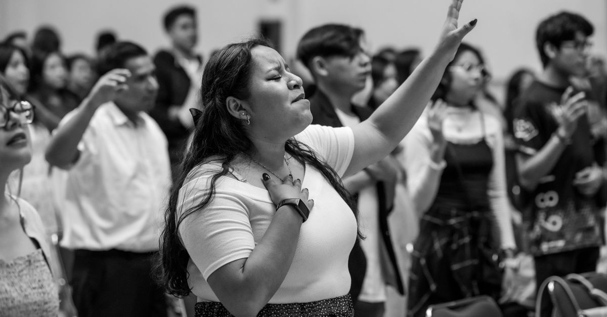 A person with a look of intense joy and tears in their eyes during a worship service, hands raised