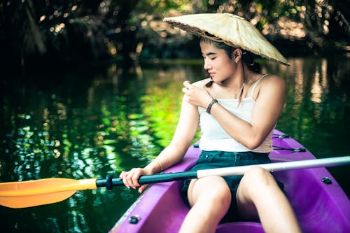 A woman in a straw hat paddling a canoe