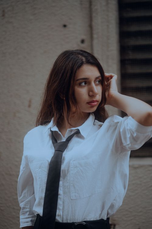 Free Portrait of a woman in a white shirt and tie, showcasing urban fashion style. Stock Photo