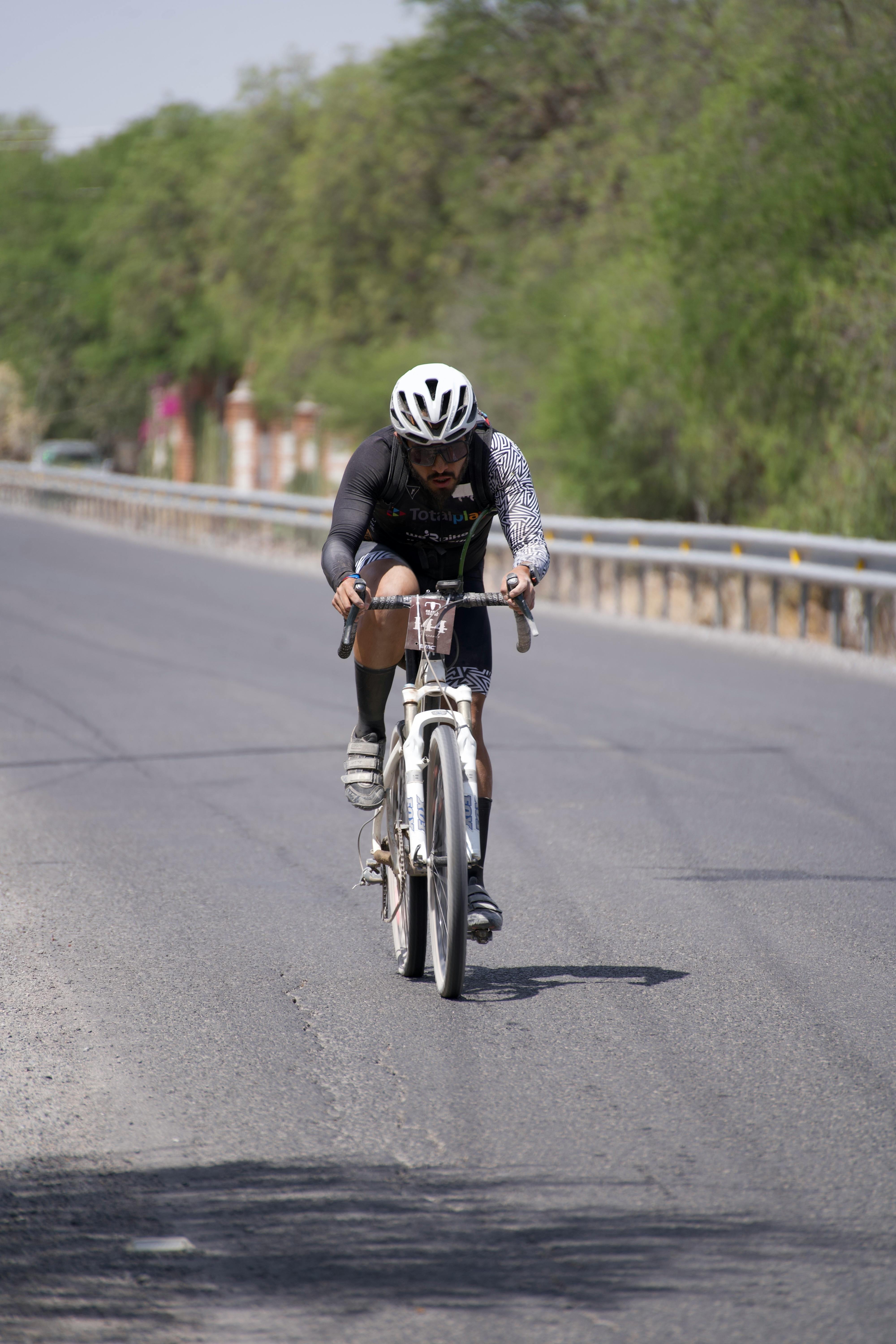 man in white helmet riding a bicycle on a road