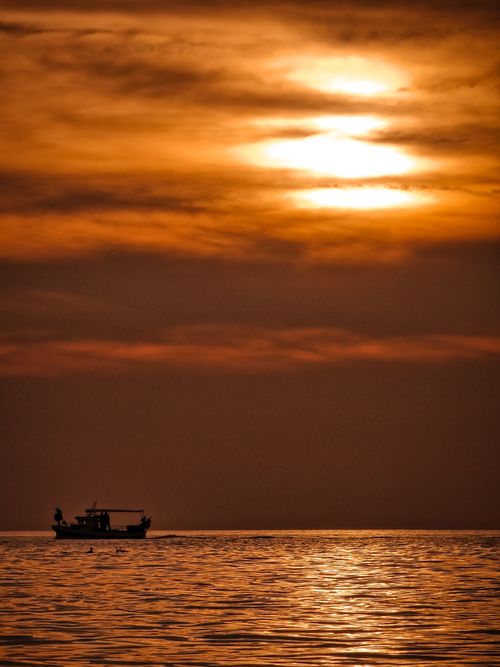 Free Tranquil scene of a vessel silhouetted against a golden sunset over the Adriatic Sea near Koper, Slovenia. Stock Photo