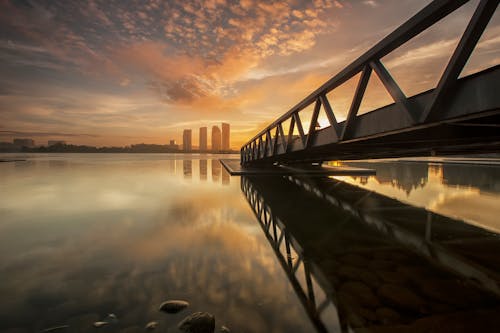Free Bridge on Body of Water Near High-rise Building during Golden Hour Stock Photo