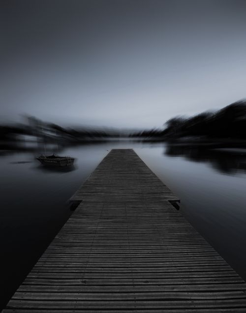 Free Peaceful black and white scene of a wooden jetty stretching into a foggy lake at dawn. Stock Photo