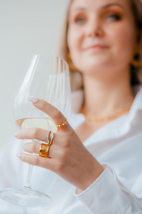 Woman Hand with Rings Holding Glass of Champagne