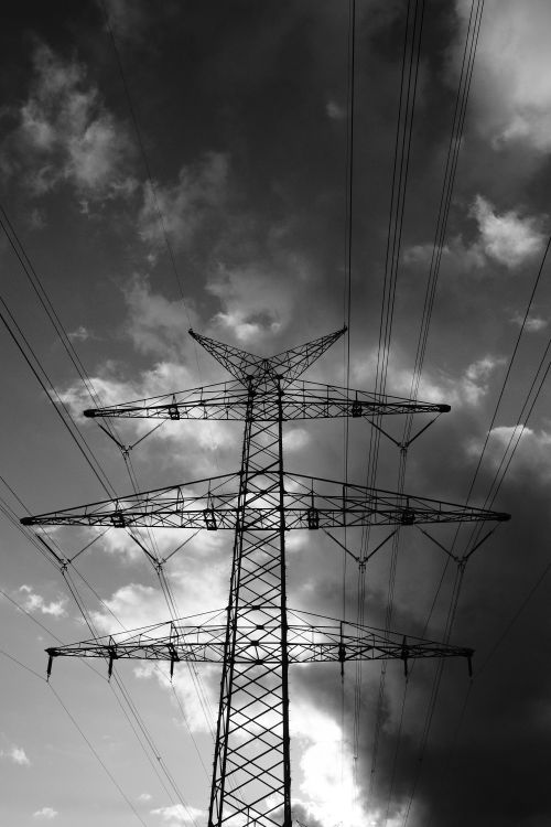 Free Striking image of power lines silhouetted against a cloudy sky, evoking industrial strength. Stock Photo