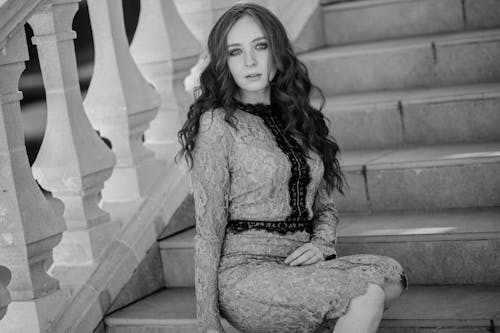 A woman in a lace dress sitting on some stairs