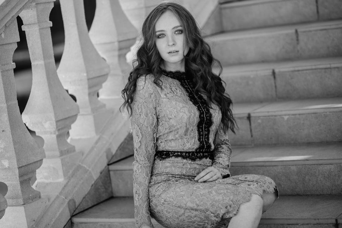 A woman in a lace dress sitting on some stairs