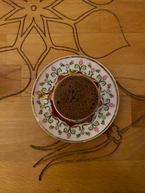 Free Top view of a coffee cup with floral saucer on a wooden table. Perfect for breakfast themes. Stock Photo