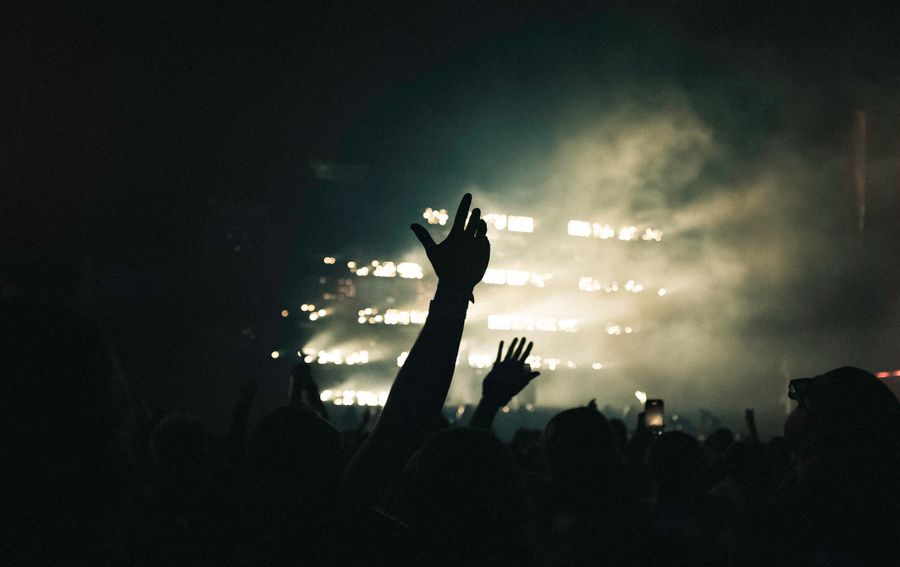 Silhouetted crowd with raised hands under stage lights — photo by Benjamin Farren on Pexels