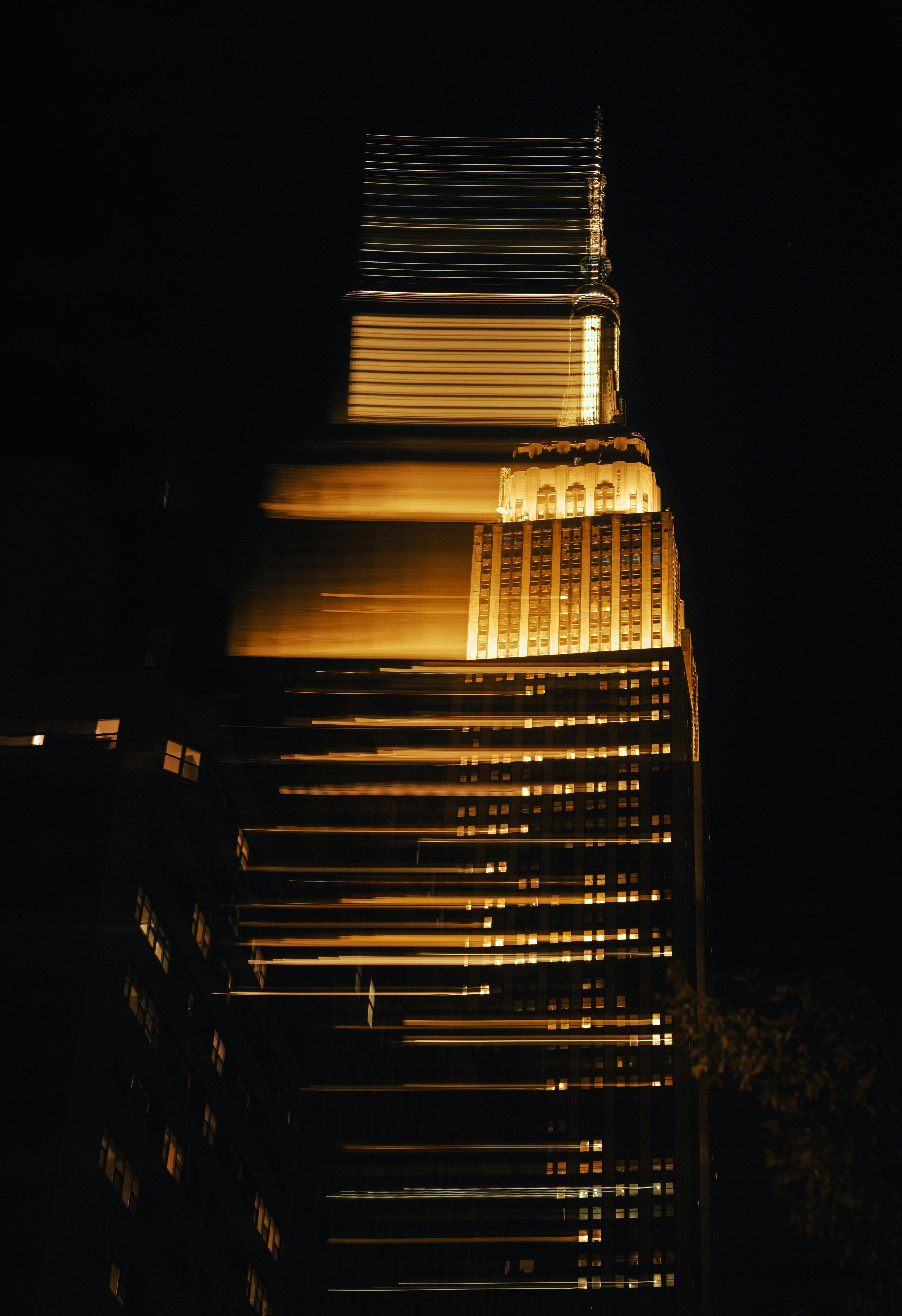 Abstract view of a skyscraper with golden light trails at night, showcasing urban elegance.