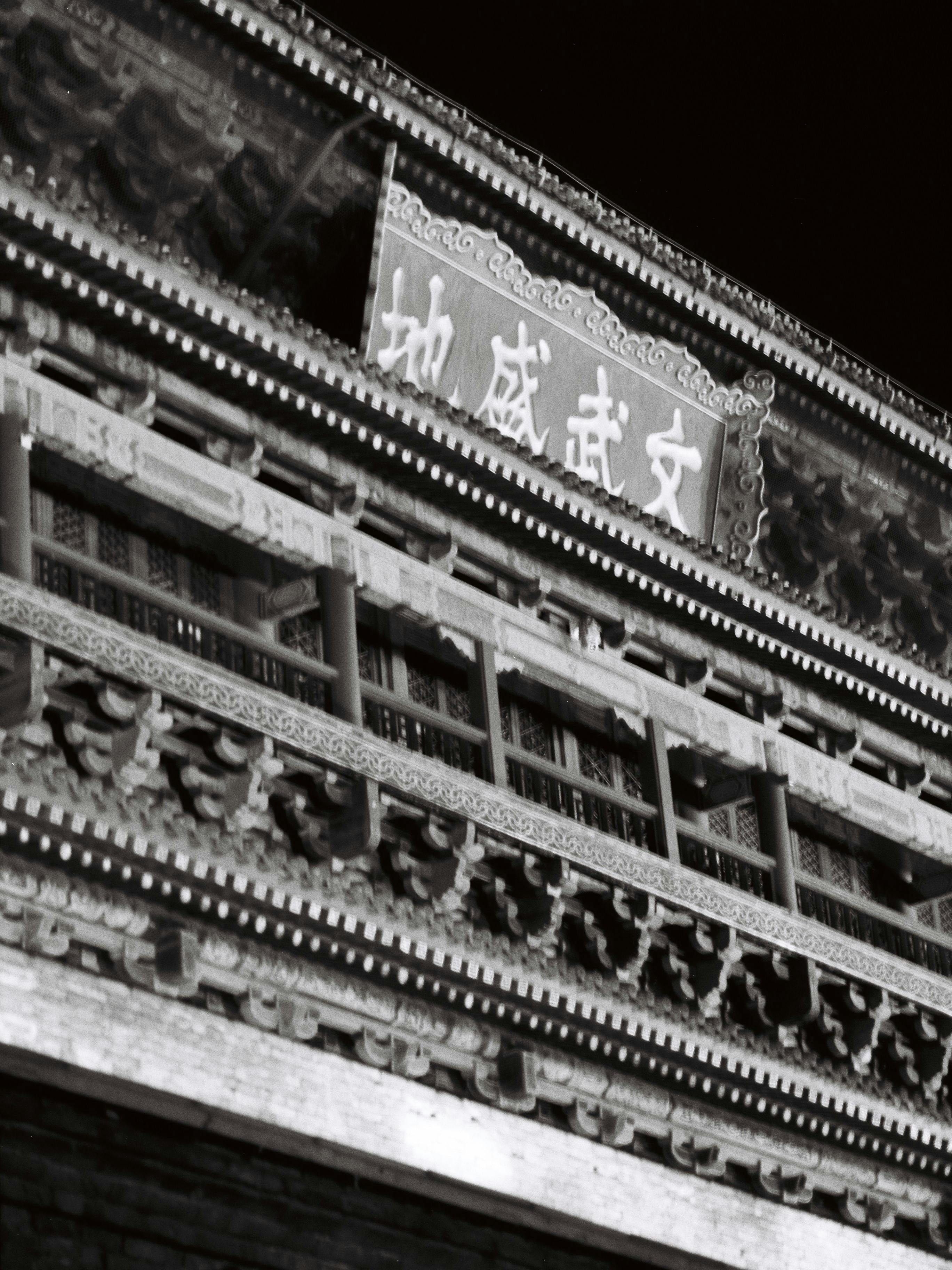 Black and white photo of a historic Chinese building facade with detailed wooden carvings.