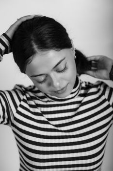 Black and white portrait of a woman with closed eyes in a striped blouse.