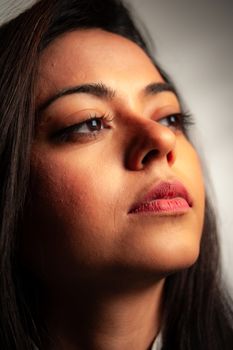 A close-up portrait of a thoughtful woman looking up, capturing emotion and detail.
