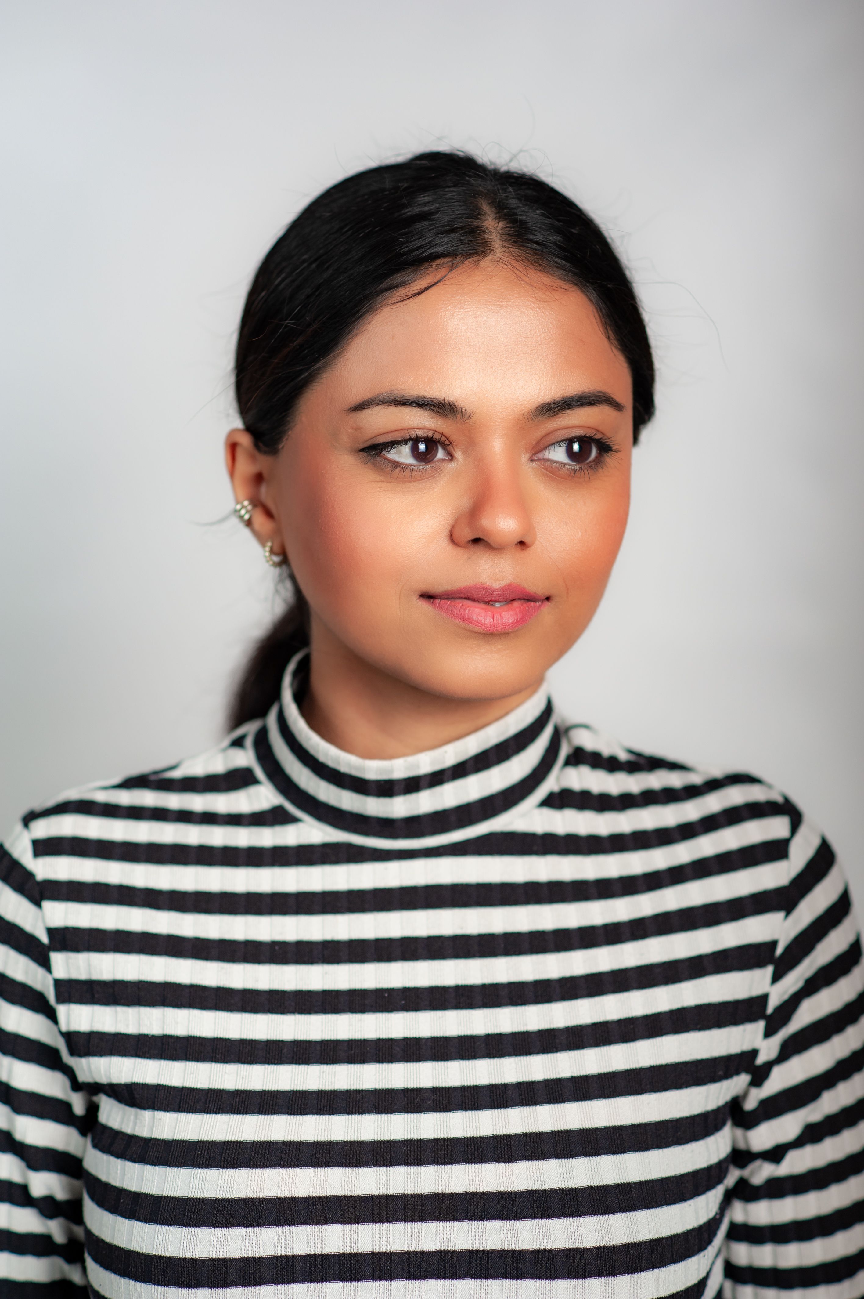 Studio portrait of a woman wearing a striped sweater against a white background.