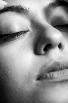A serene close-up black and white portrait of a person with eyes closed.