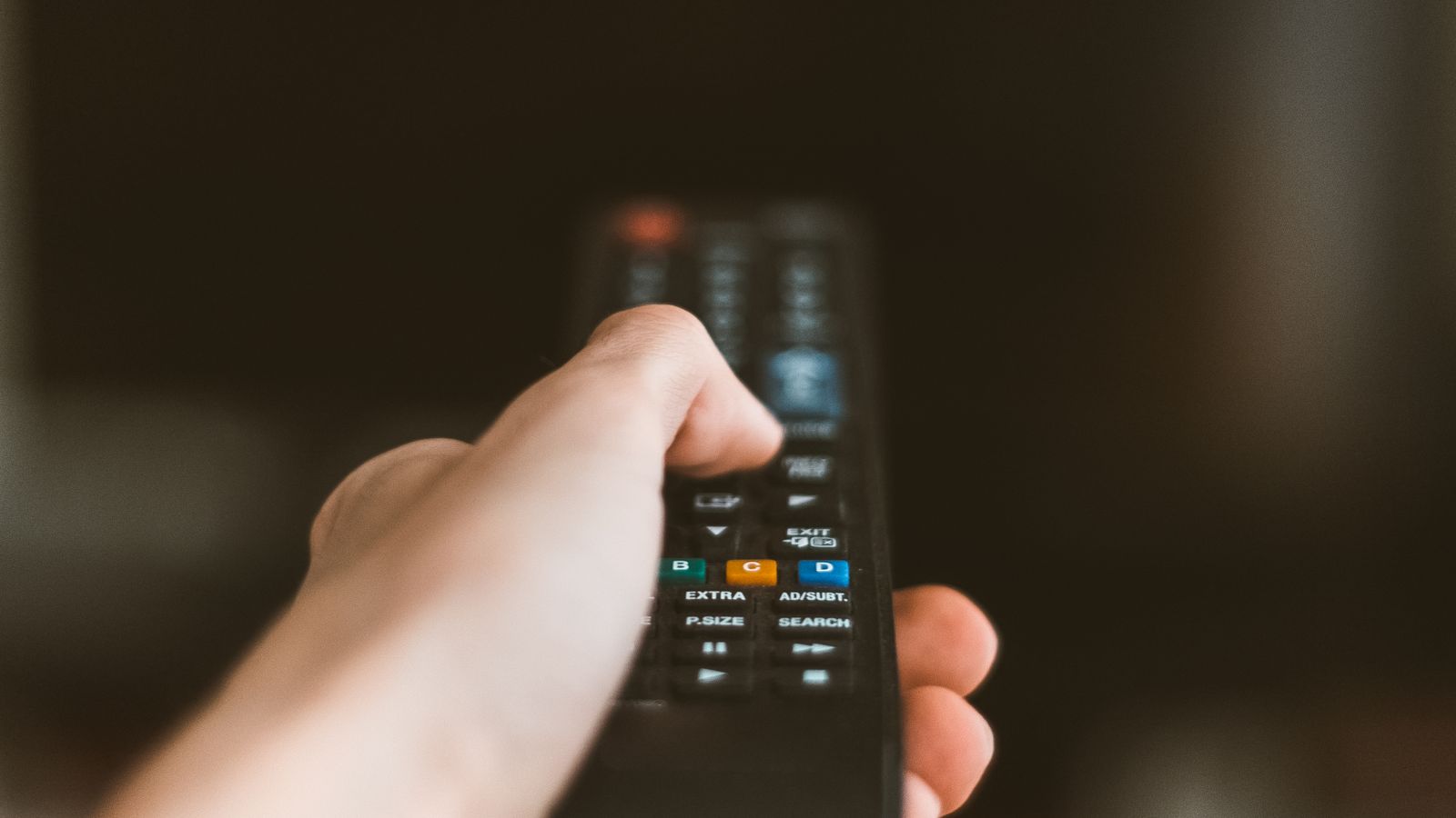 Close-up of a hand operating a television remote control