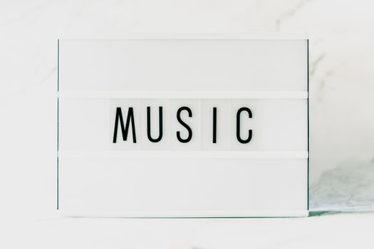 A minimalist light box displaying the word 'MUSIC' on a white background.