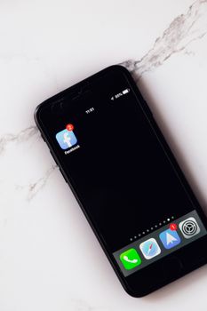 A smartphone displaying Facebook notifications lies on a marble surface, highlighting modern connectivity.