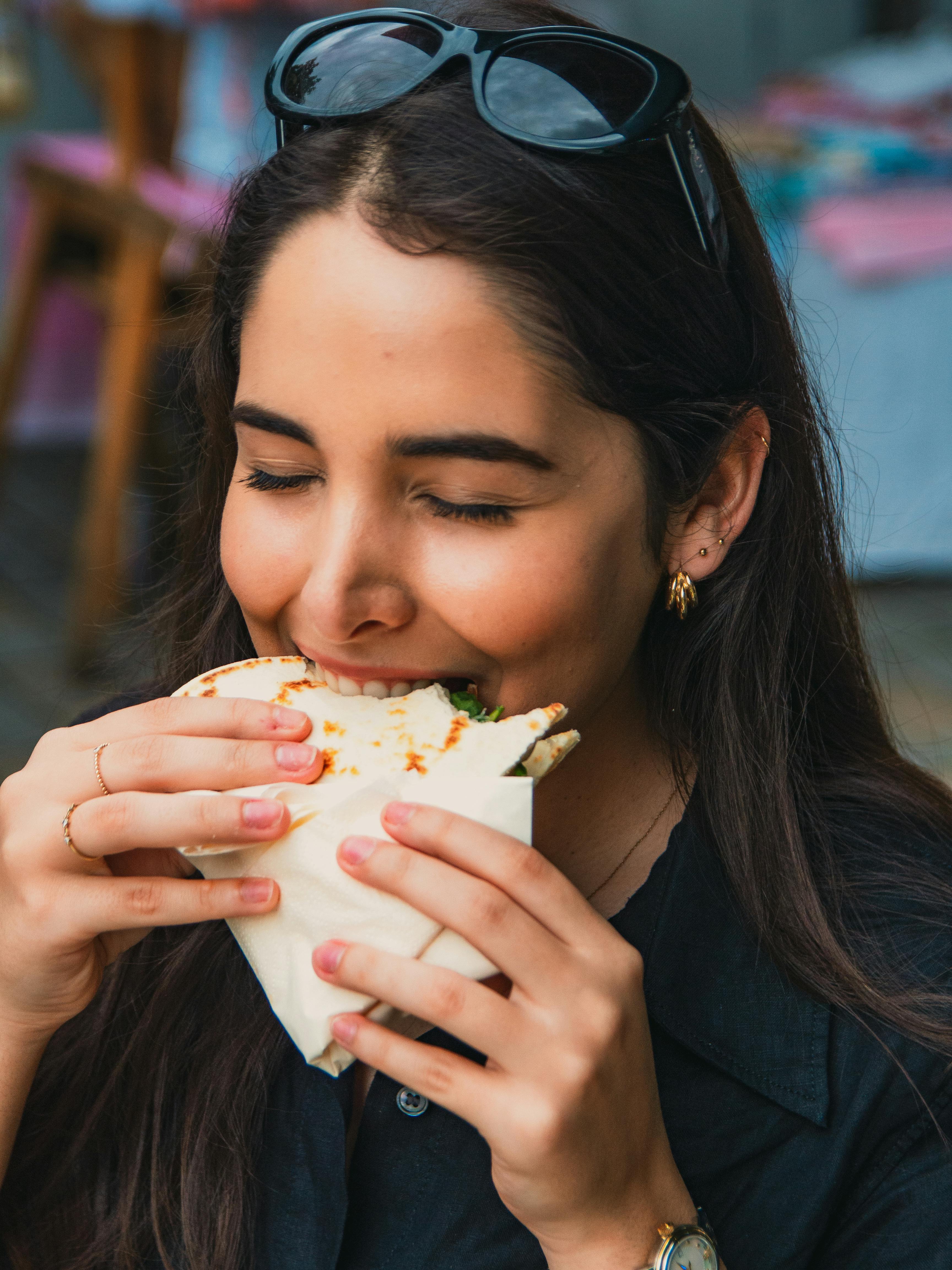 Free Woman savoring a piadina romagnola outdoors in Berlin, capturing joyful dining. Stock Photo