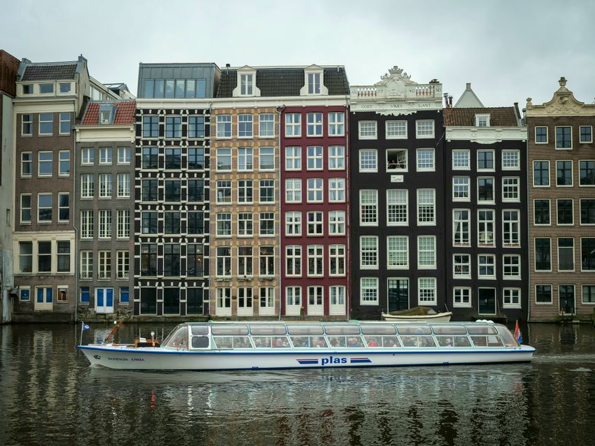 Tourists enjoying a scenic boat trip on an Amsterdam canal in the Netherlands