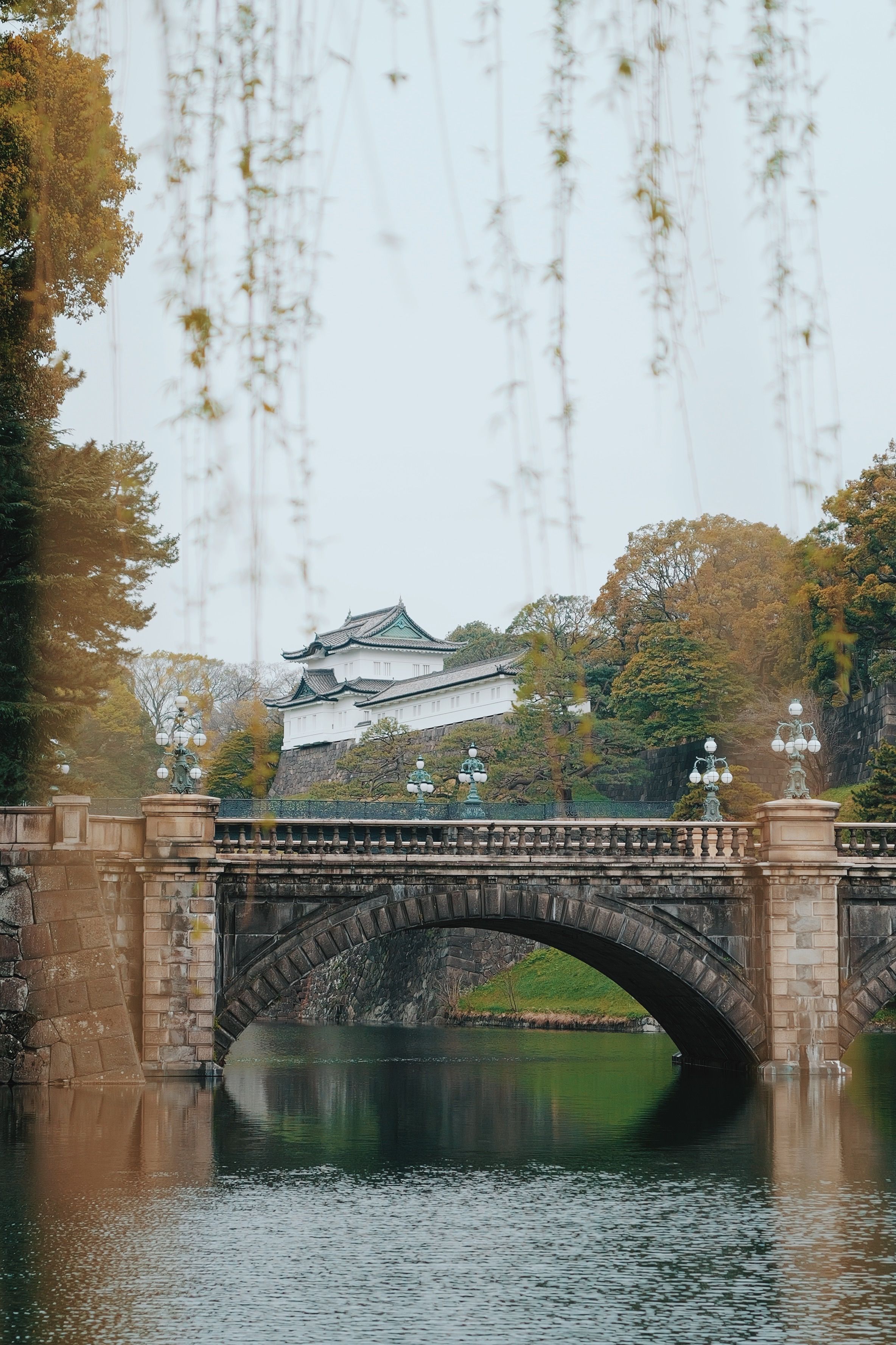 Idyllic autumn view of Nijubashi Bridge with palace backdrop in Tokyo, Japan.