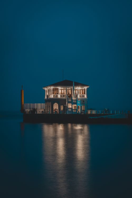 Free Illuminated Kadikoy Pier reflecting on water at night in Istanbul, Türkiye. Stock Photo