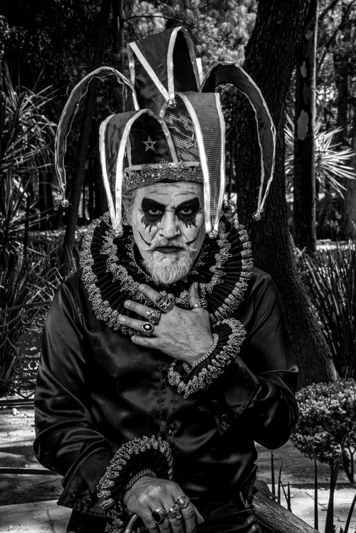 Free Artistic black and white portrait of a man in clown costume posing outdoors in a park. Stock Photo
