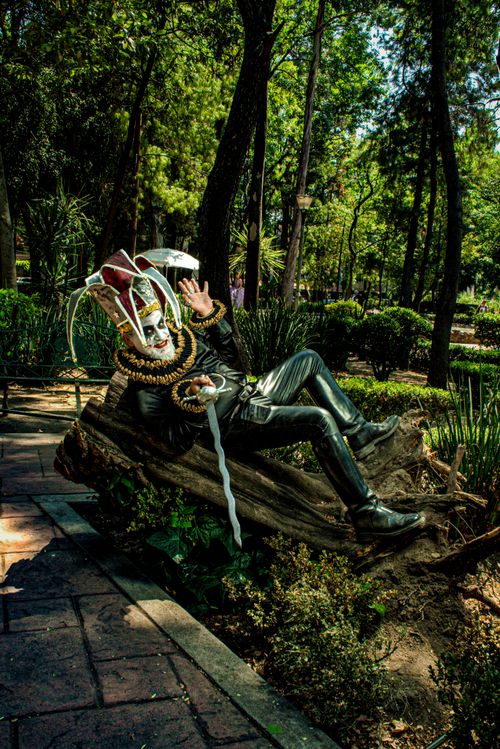Free A person dressed in a fantasy costume with face paint, lounging outdoors in a summer park setting. Stock Photo