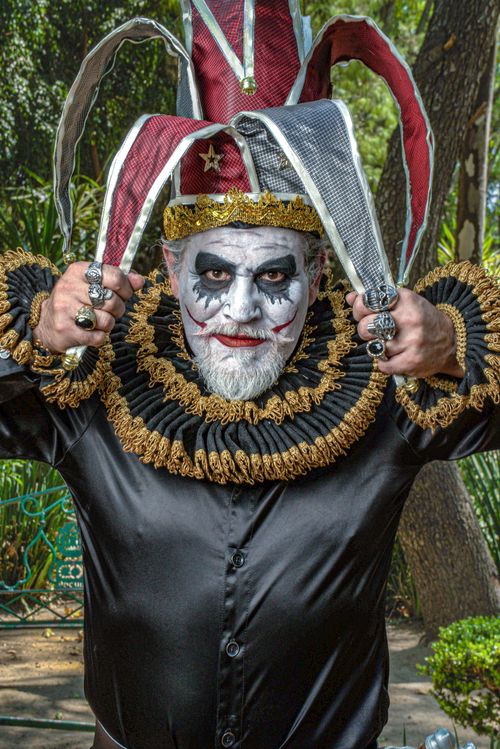 Free A dramatic jester in vibrant makeup and ornate costume poses creatively outdoors. Stock Photo