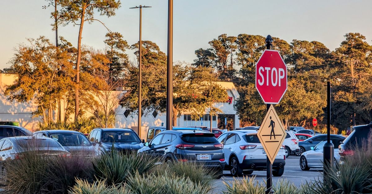 A serene parking lot scene with a stop sign, trees, and parked cars at sunset on Pawleys Island.