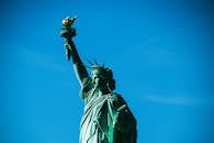 在明亮的蓝天下，自由女神像作为纽约的标志性景观，象征着自由