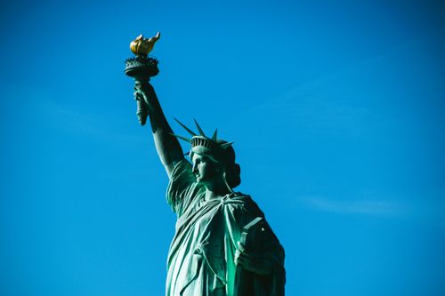 Free Iconic view of the Statue of Liberty with a bright blue sky, symbolizing freedom in New York. Stock Photo
