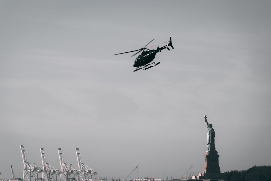 Photo of a Flying Helicopter Near Statue of Liberty