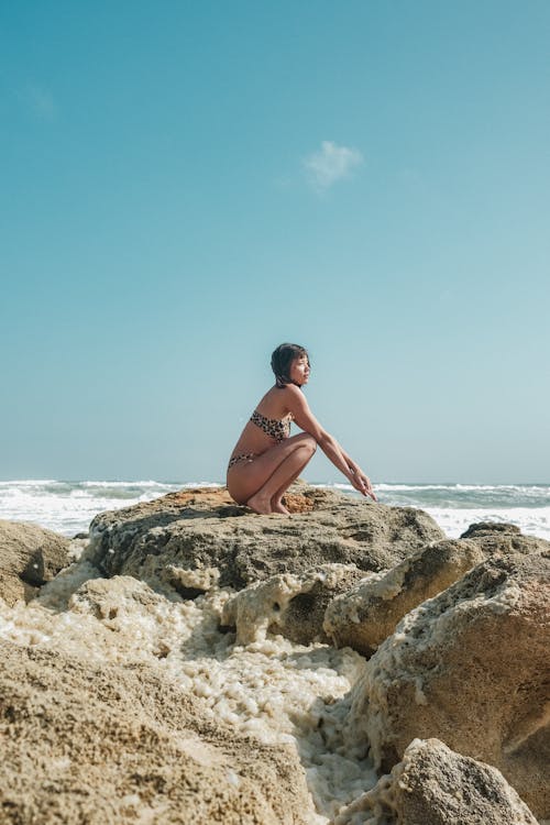 Crouching Woman in Bikini on Rock