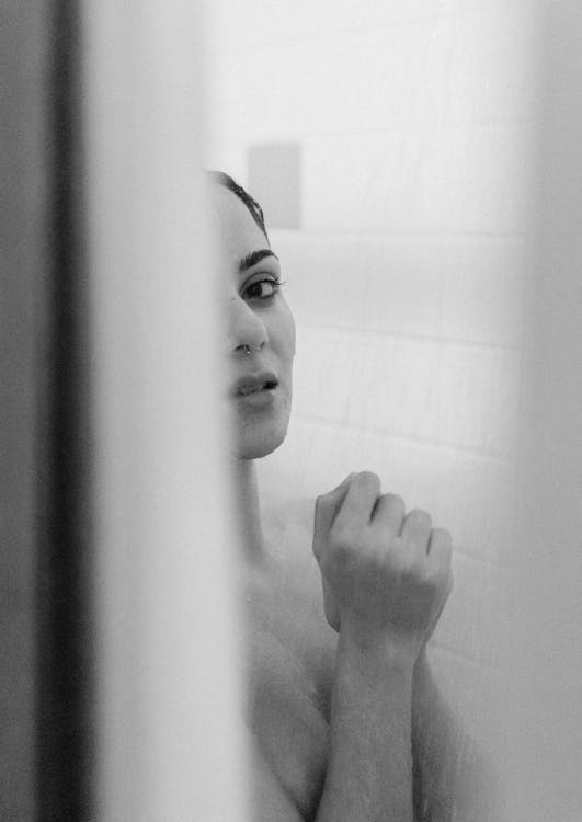 Gray scale Photo of Woman Taking Bath